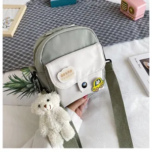 Close-up detail of cute Harajuku canvas crossbody bag with plush bear pendant and patch.