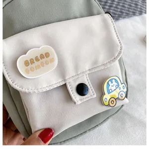 Canvas cross-body bag detail showing cute patch and pin decoration, green and beige design.