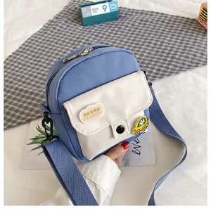 Canvas crossbody bag detail shot, blue and white cute design with patches and strap.