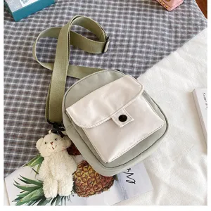 Canvas crossbody shoulder bag in light green with white front pocket and cute bear pendant.