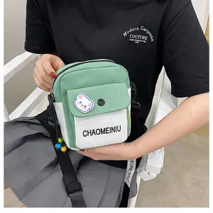 Dettaglio della borsa a tracolla in tela con design verde bianco e simpatico patch orso.