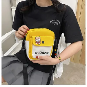Dettaglio di una borsa a tracolla in tela gialla e bianca con patch di cartone animato.