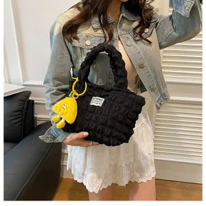 Detailed view of the black puckered handbag with cute yellow pendant, stylish daily wear.