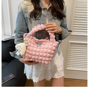 Pink puckered textured handbag detail, featuring cute plush pendant and soft quilted fabric.
