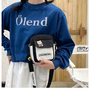 Piccola borsa a tracolla in tela con contrasto bianco e nero, stampa di lettere e ciondolo.
