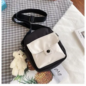 Detail view of black and white canvas crossbody bag with cute plush bear pendant and pocket.