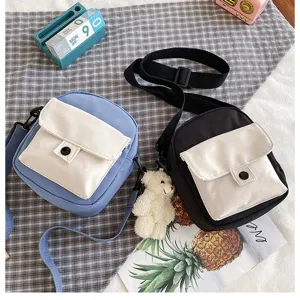Canvas crossbody bag detail showing contrast flap pocket and cute bear pendant accessory.