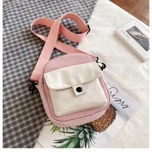 Close-up detail of the pink and off-white canvas crossbody phone bag with front pocket design.