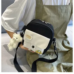 Detailed view of the cute black and white canvas crossbody bag with fluffy bear pendant for girls.