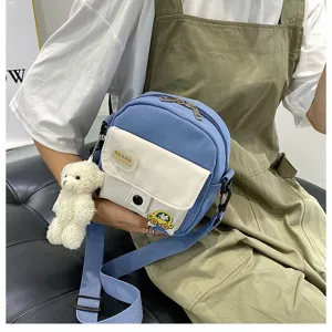 Detailed view of cute blue crossbody bag with sweet bear pendant and front pocket patch.