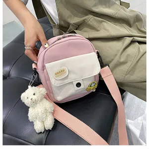 Close-up detail of the cute pink and white canvas crossbody bag with fluffy bear pendant.