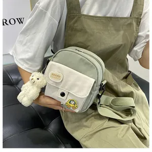 Detailed view of the cute Japanese style canvas crossbody bag with bear pendant for girls.