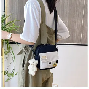 Detailed shot of casual canvas crossbody bag with small bear pendant and cute pocket patch.