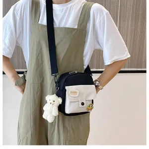 Detail view of cute canvas crossbody bag with bear pendant and front pocket design for girls.