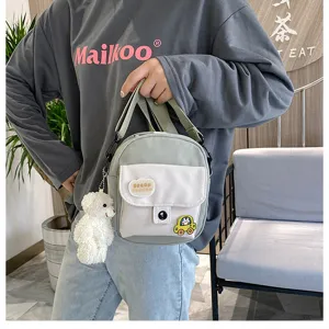 Detailed view of a cute canvas crossbody bag with bear pendant and patches for students.