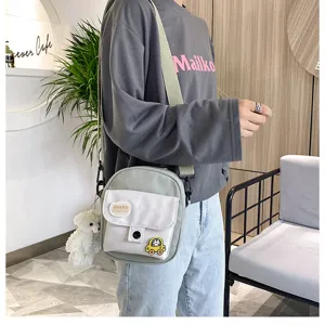 Detailed view of casual canvas crossbody bag with cute bear pendant and front pocket design.