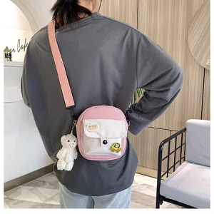 Pink canvas crossbody bag with cute bear pendant, stylish casual shoulder phone bag for girls.