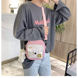 Cute Japanese Harajuku canvas crossbody bag pink student phone shoulder bag with plush bear pendant.