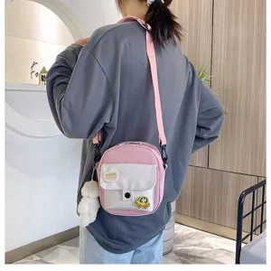 Details of the cute pink crossbody canvas bag with plush bear pendant and front pocket design.