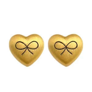 French vintage matte gold heart bow earrings detail closeup view, elegant metallic texture.
