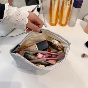 Detail van een glinsterende zilveren cosmetisch tasje, met ruime binnenkant en make-upkwasten.