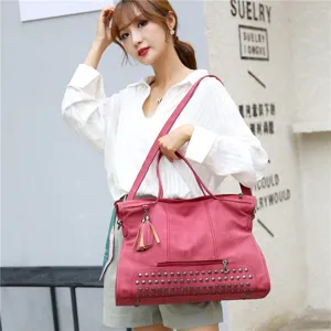 Detailed view of large pink PU leather shoulder bag with chic studs and elegant tassel charm.