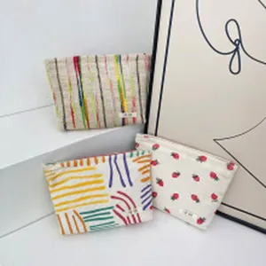 Detail van canvas make-uptas, schattig aardbeien- en abstract strepenpatroon van dichtbij.