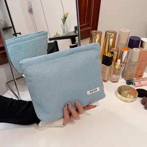 Gedetailleerd overzicht van glitterende blauwe cosmetische tas met zachte etui en wit logo-label.