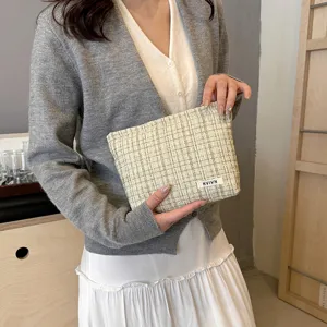 Close-up view of the elegant tweed cosmetic pouch showcasing texture and stylish woven label detail.