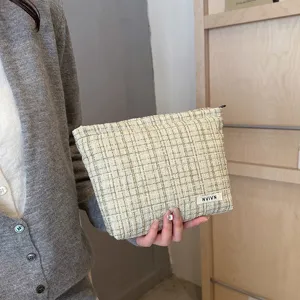 Detailed close-up of a chic tweed cosmetic pouch featuring a secure zipper and minimalist woven label.