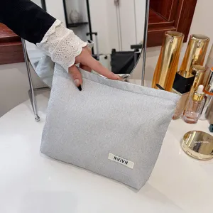 Zilver glitter cosmetisch tasje detail toont glinsterende stof textuur en merklabel dichtbij.