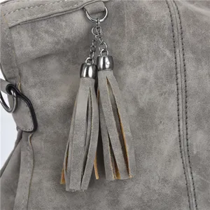 Grey PU leather handbag detail close-up showing texture, metal chain, and stylish tassels.