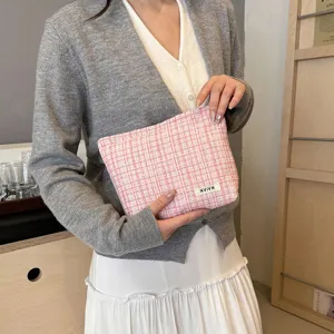 Pink tweed cosmetic bag with elegant plaid pattern and small logo tag, ideal for daily makeup.
