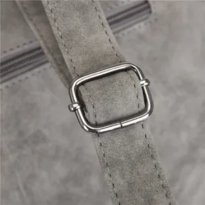 Grey PU leather bag strap metal buckle detail close up, textured finish, durable hardware.