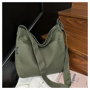 Canvas shoulder bag detail showing dark green fabric, wide strap and side pocket design.