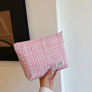 Pink tweed cosmetic pouch with zipper closure, soft woven fabric makeup storage bag detail.