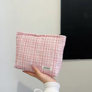 Close-up detail of the pink tweed cosmetic pouch showing textured woven fabric and brand tag.