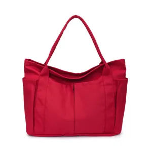 Red canvas tote bag detail, multi-pocket design, durable fabric, casual everyday shoulder bag.