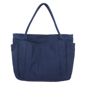 Dark blue canvas tote bag detail, featuring durable fabric, front pockets and double straps.