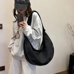 Detail view of the black nylon hobo shoulder bag worn crossbody in a daily casual outfit.
