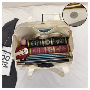 Canvas tote bag detail showing large capacity interior compartments and secure magnetic snap closure.