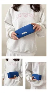 Detailed shot of the blue canvas pencil bag held by model, showing texture and zipper.