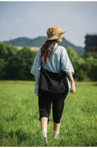 Outdoor-Lifestyle-Detailaufnahme einer schwarzen Canvas-Umhängetasche im grünen Feld.