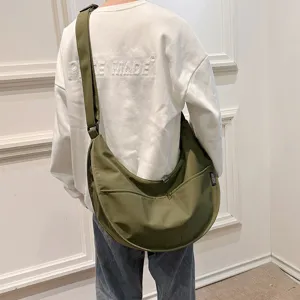 Detail view of the dark green canvas dumpling crossbody bag, showing its soft curved shape.