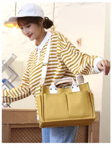 Yellow canvas shoulder bag detail view, showcasing large capacity and sturdy white straps.