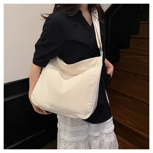 Detailed shot of a casual canvas shoulder bag worn by a model indoors, large capacity.