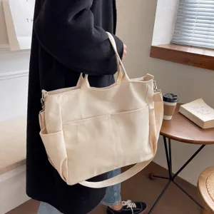 Casual multi-pocket canvas tote bag for women, stylish shoulder handbag with adjustable strap.