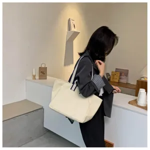 Casual canvas tote bag with striped shoulder straps shown in a stylish modern cafe setting.