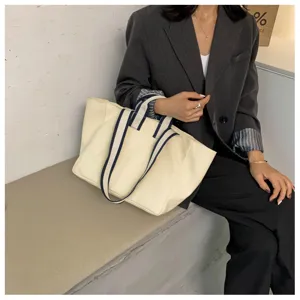Canvas tote bag detail view showing casual commuter style and durable striped handles.