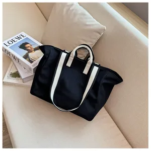 Black canvas tote bag with white straps, minimalist large capacity shoulder bag detail.